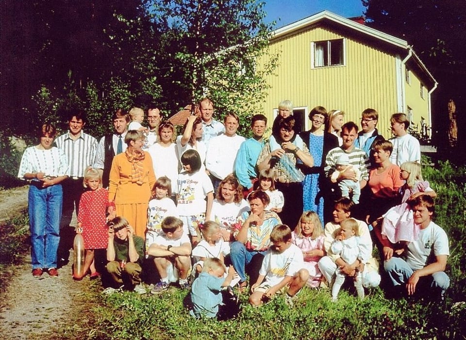 Stort gruppfoto av Forsbergs-släkten framför ett gult hus, sommaren 1992.