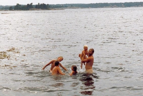 Björn badar i en sjö tillsammans med sina barn.
